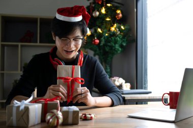 Mutlu Asyalı adam elinde kırmızı kurdeleli Noel hediyesi kutusu tutuyor..