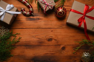 Hediyeler, köknar ağacı dalları, ahşap arka planda kırmızı süslemeler. Düz konum, üst görünüm, kopyalama alanı.