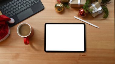 Dijital tablet, kahve fincanı, stilus kalem ve Noel hediyeleri ahşap masada..