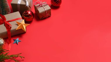 Kırmızı arka planda hediye kutuları ve köknar dalları var. Noel ve Yeni Yıl kavramı.