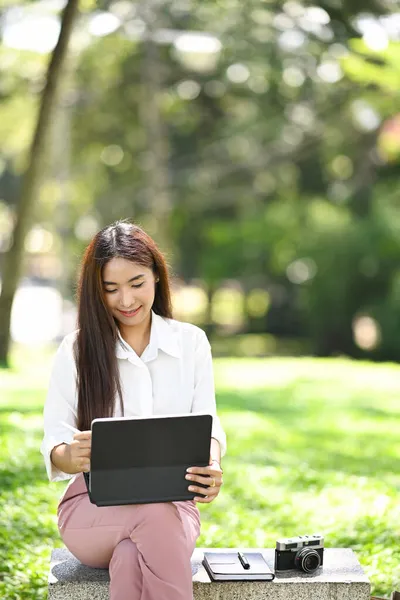 微笑的女人坐在公园的长椅上 用着电脑平板电脑 — 图库照片