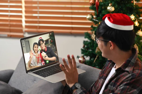Młody Człowiek Czerwonym Kapeluszu Mikołaja Mając Rozmowę Wideo Laptopie Przyjaciółmi — Zdjęcie stockowe