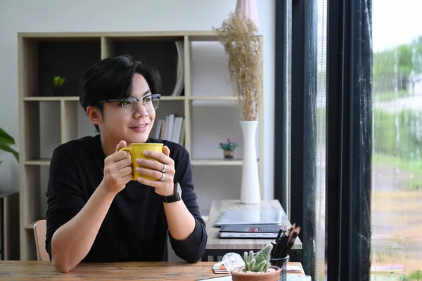 Pozitivní Mladý Asijský Muž Drží Šálek Kávy Dívá Okna — Stock fotografie