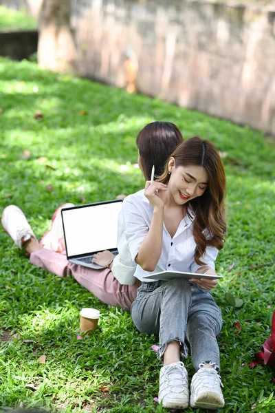 两个快乐的亚洲女人坐在公园的绿草上 用电脑笔记本电脑工作 — 图库照片