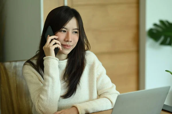 Młoda Azjatka Ciepłych Ubraniach Pracuje Laptopem Komputerowym Rozmawia Przez Telefon — Zdjęcie stockowe