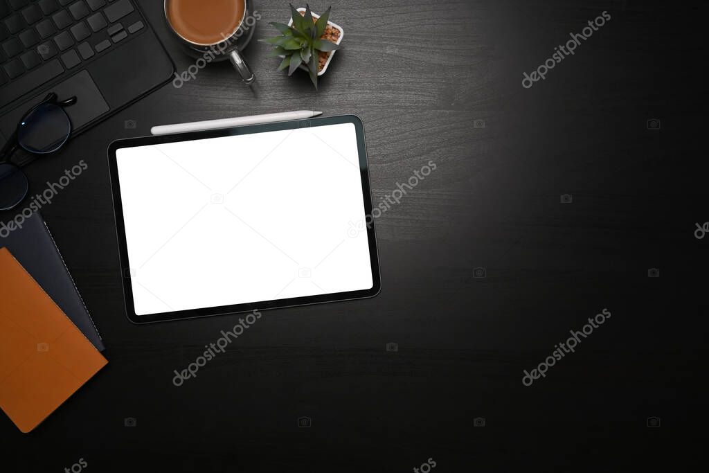 Mock up digital tablet, stylus pen, notebooks and coffee cup on black table.