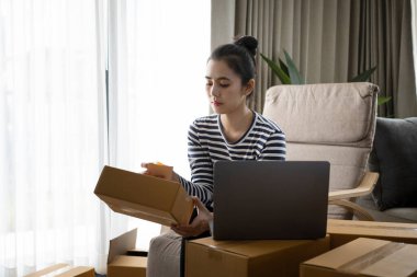 Küçük işletme sahipleri bilgisayardan siparişleri kontrol ediyor ve müşteriye teslimat için paket hazırlıyorlar.