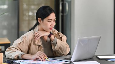 Yaratıcı ofiste bilgisayarla çalışan genç bayan grafik tasarımcısı.