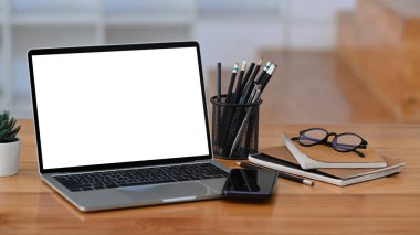 Bilgisayar dizüstü bilgisayar, akıllı telefon, kalem tutacağı ve ahşap masadaki kitaplar..