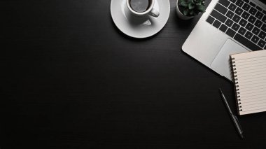 Bilgisayar laptopunu, not defterini ve kahve fincanını siyah masaya yapıştır.