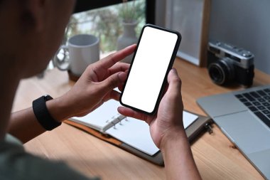 Omzunun üstünden, boş ekranlı akıllı telefon tutan Asyalı genç adamın görüntüsü..