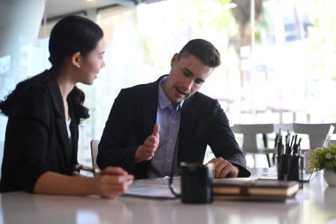 İş adamı, iş arkadaşıyla proje planlamasını tartıştı ve mali veri raporu hakkında tavsiyelerde bulundu.