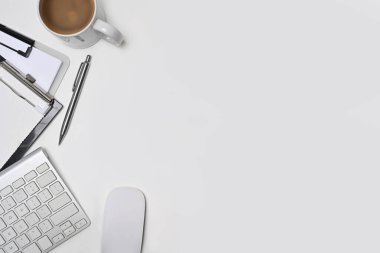Kahve fincanı, dosya ve kablosuz klavyeli beyaz ofis masası..