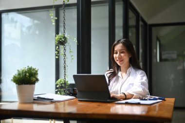 Ofiste bilgisayar tabletiyle çalışan mutlu Asyalı kadın..