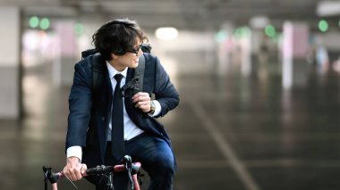 Asyalı işadamı bisikletle işe gidiyor. Çevre Taşımacılığı ve sağlıklı aktif yaşam tarzı kavramı.