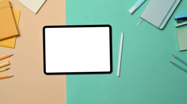 Boş ekran ve renkli arkaplan üzerindeki kırtasiye malzemesi ile dijital tableti düzenle.