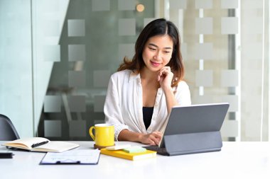 Ofiste otururken bilgisayardaki e-postaları kontrol eden Asyalı iş kadını.