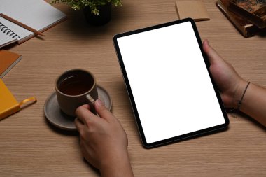 Yakından bak, elinde kahve fincanı olan ve dijital tablet kullanan genç adam..