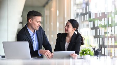 İki iş adamı modern ofiste proje planlamasını tartışıyor..