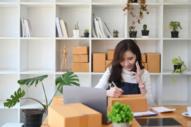 Küçük işletme girişimcisi cep telefonundan müşteri siparişlerini doğruladı.