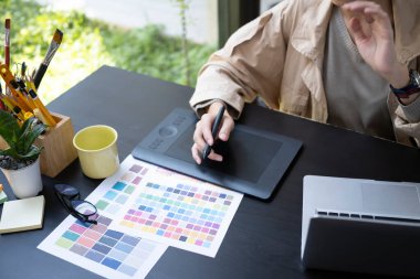 Ofiste grafik tablet ve renk örneğiyle çalışan genç bir kadın..