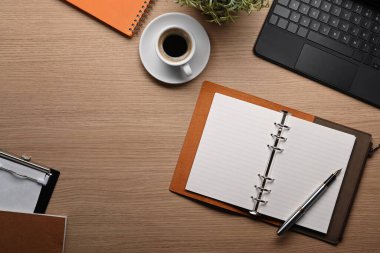 Not defterinin üstünde, kahve fincanı ve bilgisayar laptopu ahşap masada..