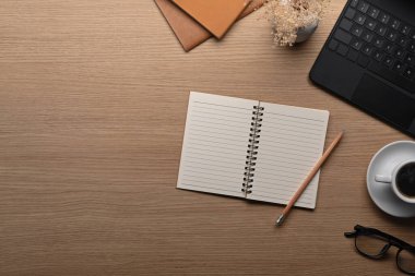 Üst görünüm defteri, dizüstü bilgisayar ve kahve fincanı ahşap masada..