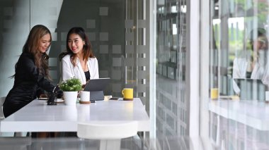 Modern iş yerinde iki iş arkadaşı birlikte proje üzerinde çalışıyor..