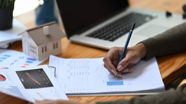 Bayan emlakçı ofis masasındaki mali belgeleri kontrol ediyor..
