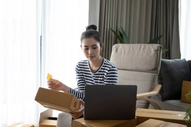 Genç işletme sahibi müşteriye teslimat için bir paket ürün hazırlıyor..