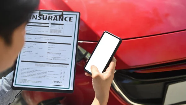 保险代理人在车祸后检查车辆时使用智能手机 — 图库照片