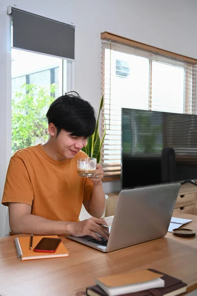 뜨거운 커피를 마시고 집에서 컴퓨터로 인터넷 서핑을 젊은이 — 스톡 사진