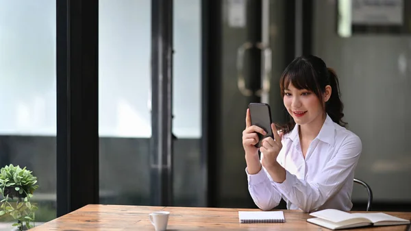 Uśmiechnięta Azjatka Siedzi Biurze Używa Smartfona — Zdjęcie stockowe