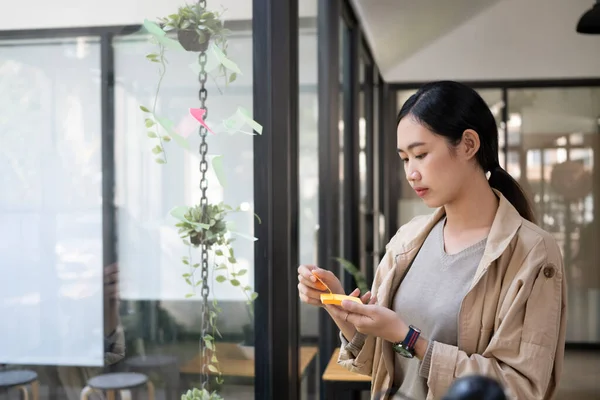 Jonge Aziatische Vrouw Het Schrijven Van Informatie Plakkerige Notities Terwijl — Stockfoto