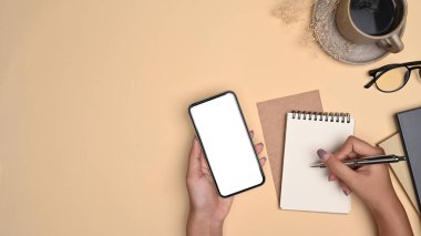 Yukarıdan bakan kadın elinde akıllı telefon reklamı tutuyor. Not defterine not alıyor..