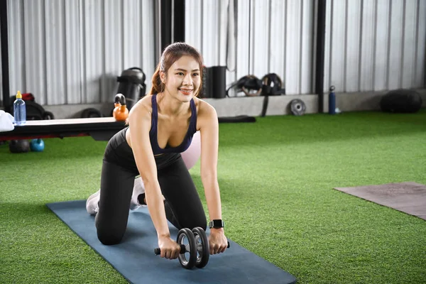 Gülümseyen sporcu kadın spor salonunda karın silindiriyle antrenman yapıyor..