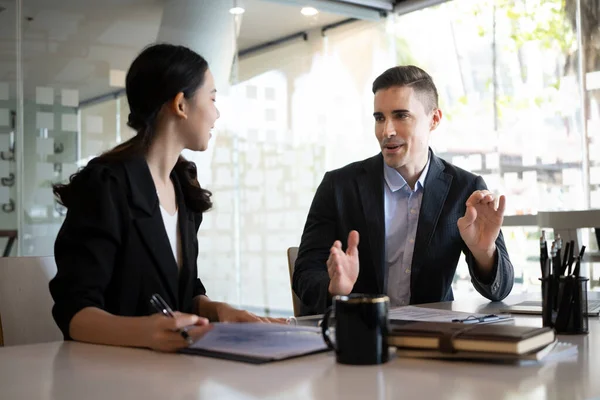 Modern ofiste yeni proje planlaması için tartışan iki kendine güvenen iş adamı.