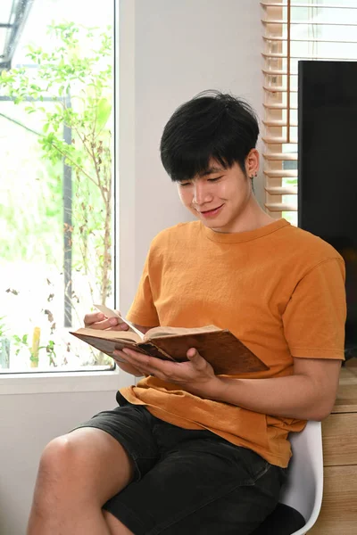 Smiling Young Asian Man Reading Book Living Room — Fotografia de Stock