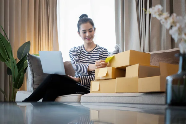 Gülümseyen küçük işletme sahibi müşteriye teslimat için paket hazırlıyor.