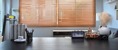 Home office interior. Books, pencil holder, coffee cup and potted plant on wooden table.