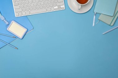 Flat lay notebook, keyboard and plastic badge on blue background.