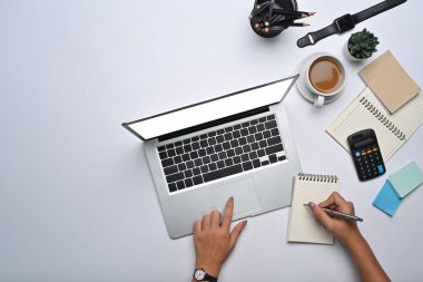 Üst düzey iş kadını dizüstü bilgisayar kullanıyor ve not defteri üzerinde notlar alıyor..