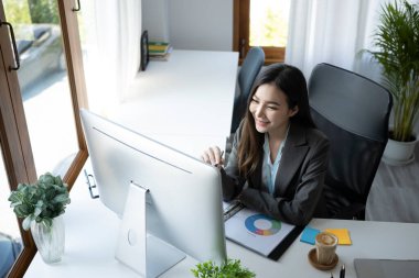 Modern ofiste bilgisayarla çalışan çekici bir iş kadını..