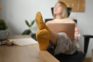 Mutlu Asyalı kadın evdeki rahat koltukta dizüstü bilgisayar kullanıyor..