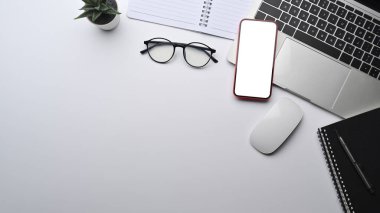 Top view smart phone, laptop computer and glasses on modern workspace.