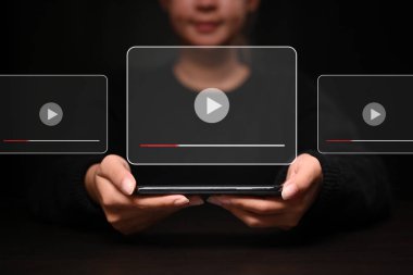 Sanal ekranda oynatma düğmesi olan dijital tableti tutan gülümseyen kadın.