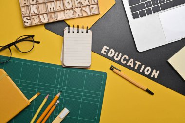 Above view laptop computer, glasses and stationery on yellow background. Back to school concept.