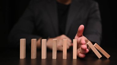 İşadamı, dominoları durdurmaya çalışıyor. Finansmanı domino etkisi kavramından korumak.