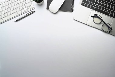 Top view white office desk with computer laptop, notebook and glasses.