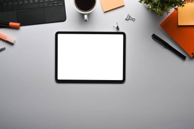 Mock up digital tablet with blank screen and office supplies on white table.